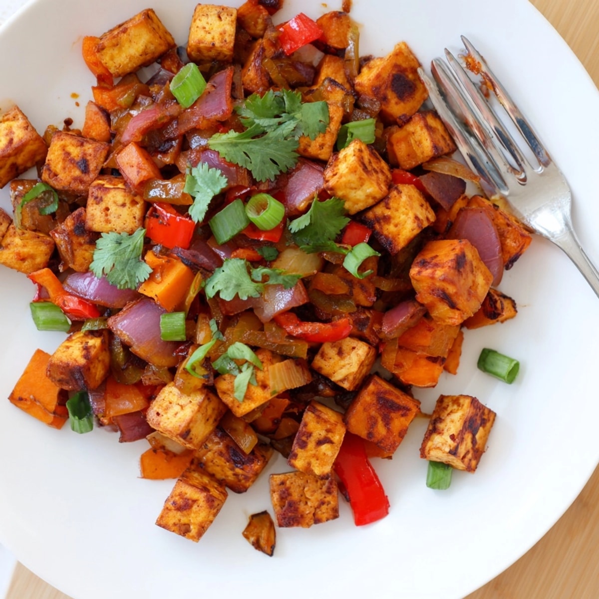Herzhafter BBQ Tofu & Süßkartoffel-Hash, goldbraun gebraten, mit frischen Kräutern garniert für ein köstliches Essen.