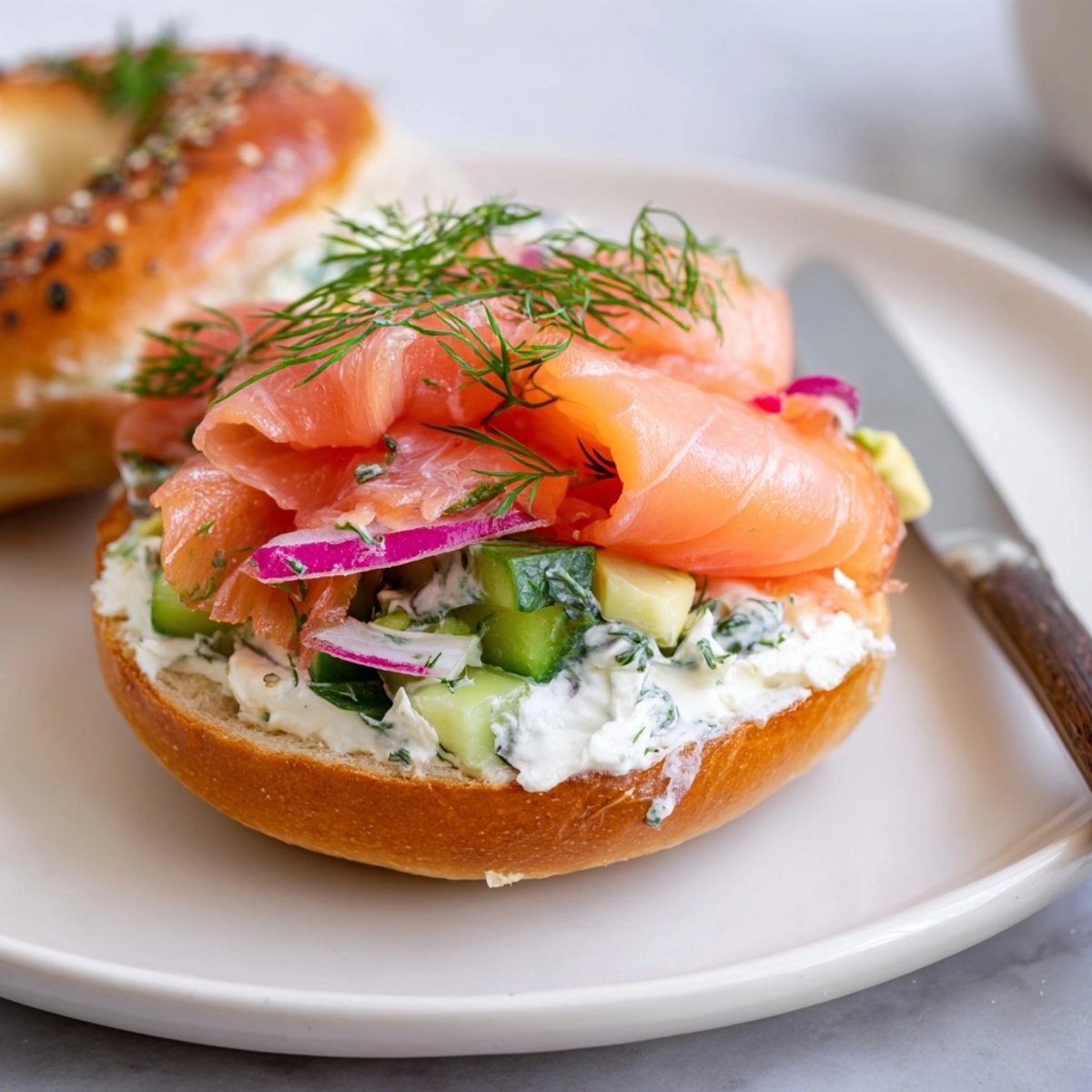Leckere Smoked Salmon & Dill Bagel Sandwiches, belegt mit Lachs, Gurke und roten Zwiebeln.