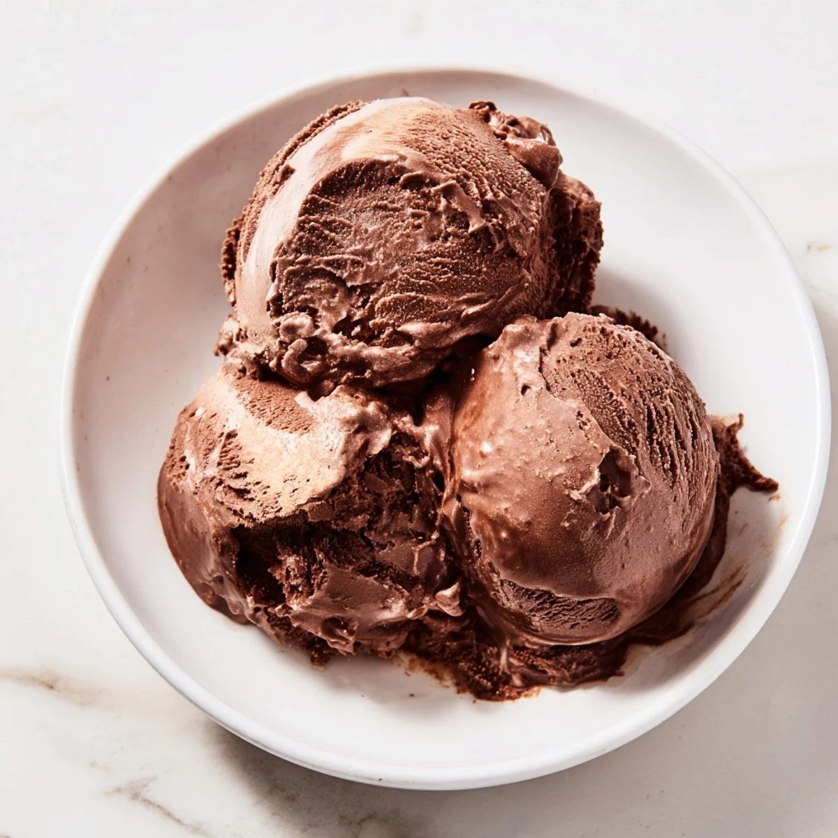 Creamy, rich chocolate ice cream swirled in a bowl, promising a deeply satisfying dessert experience.