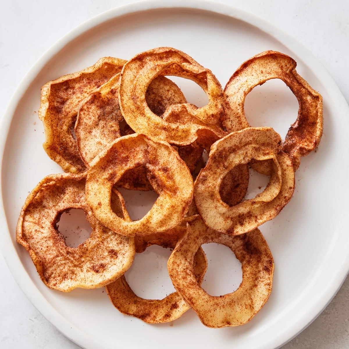 Thin, golden spiced apple chips with visible cinnamon sugar; a delightful and healthy snack.