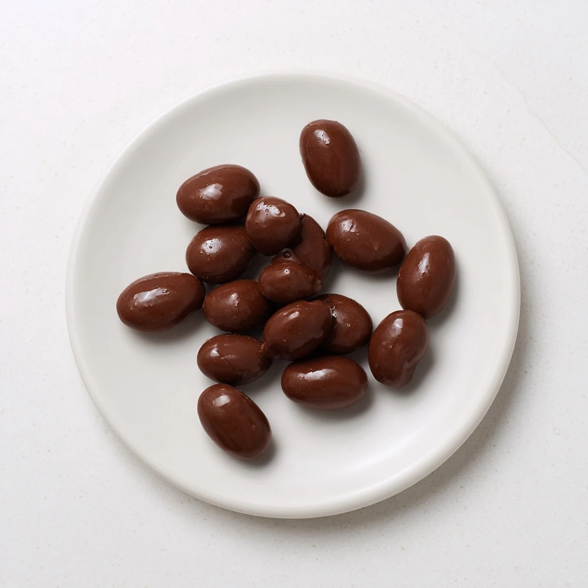 Rich, dark chocolate covered raisins glistening on a parchment-lined baking sheet, ready to cool.