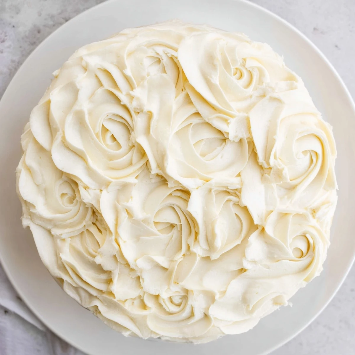 Close-up of a bowl filled with smooth, vanilla buttercream frosting, ready to be spread.