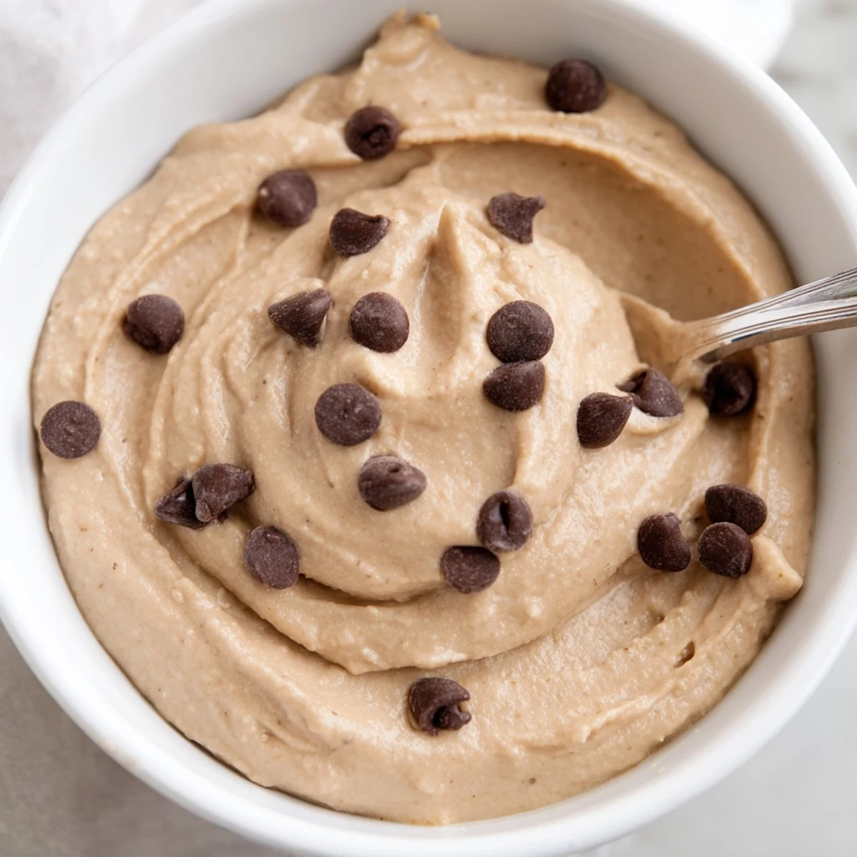 Creamy Chocolate Chip Cookie Dough Hummus swirled with chocolate chips, ready for dipping pretzels.