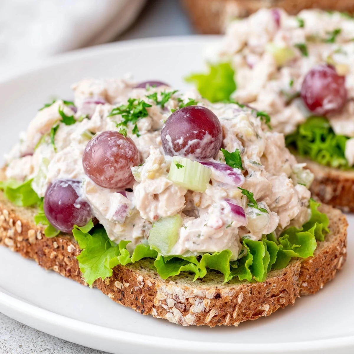Creamy chicken salad sandwich with grapes, served on toasted bread with fresh lettuce, perfect for lunch.