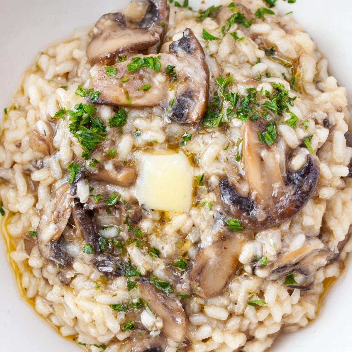 Goldbraune Mushroom Risotto with Truffle Oil auf einem Holzbrett, serviert mit gehobeltem Parmesan.