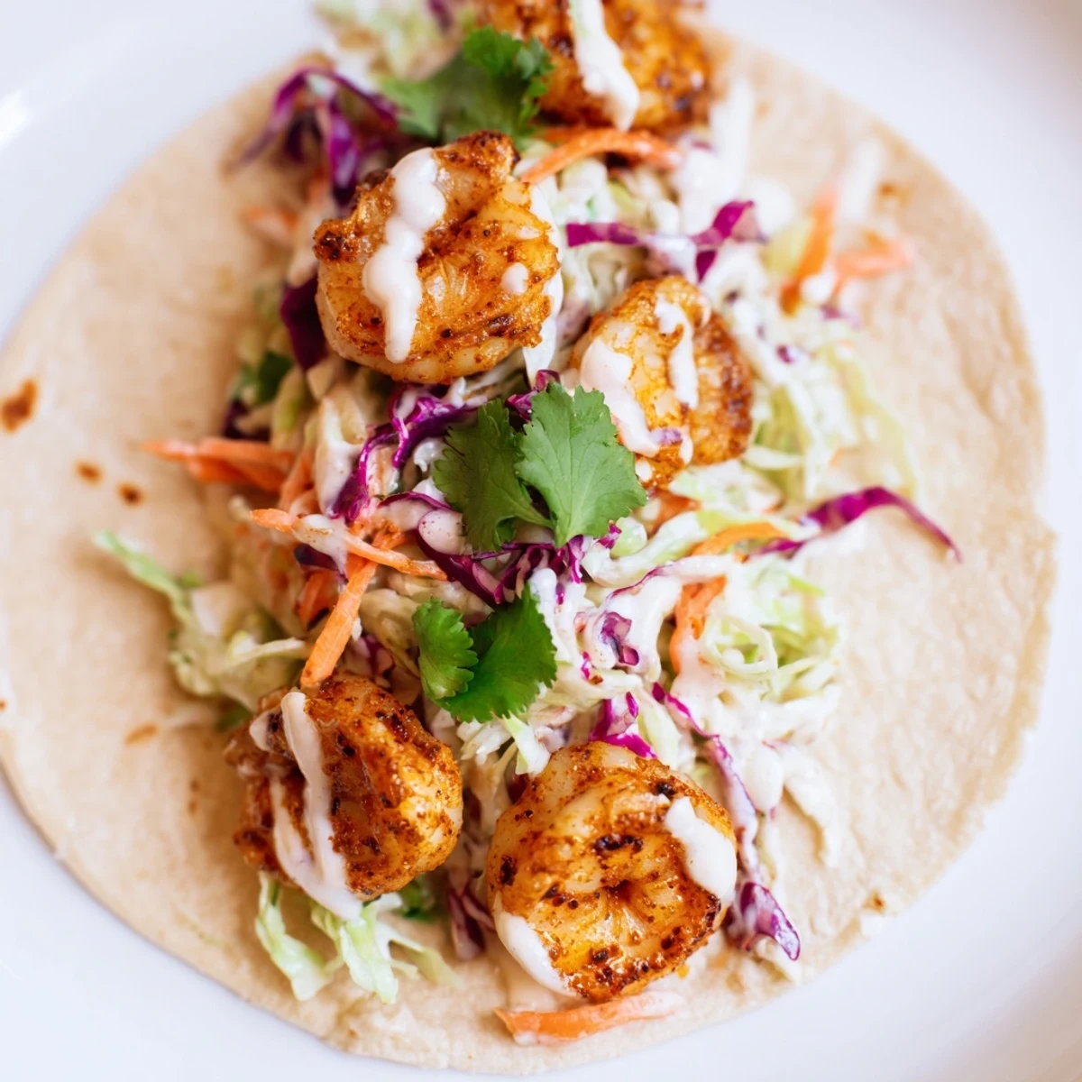 Genussvolle Cajun Shrimp Tacos mit cremiger Avocado-Scheibe und frisch gepresster Limette am Teller.