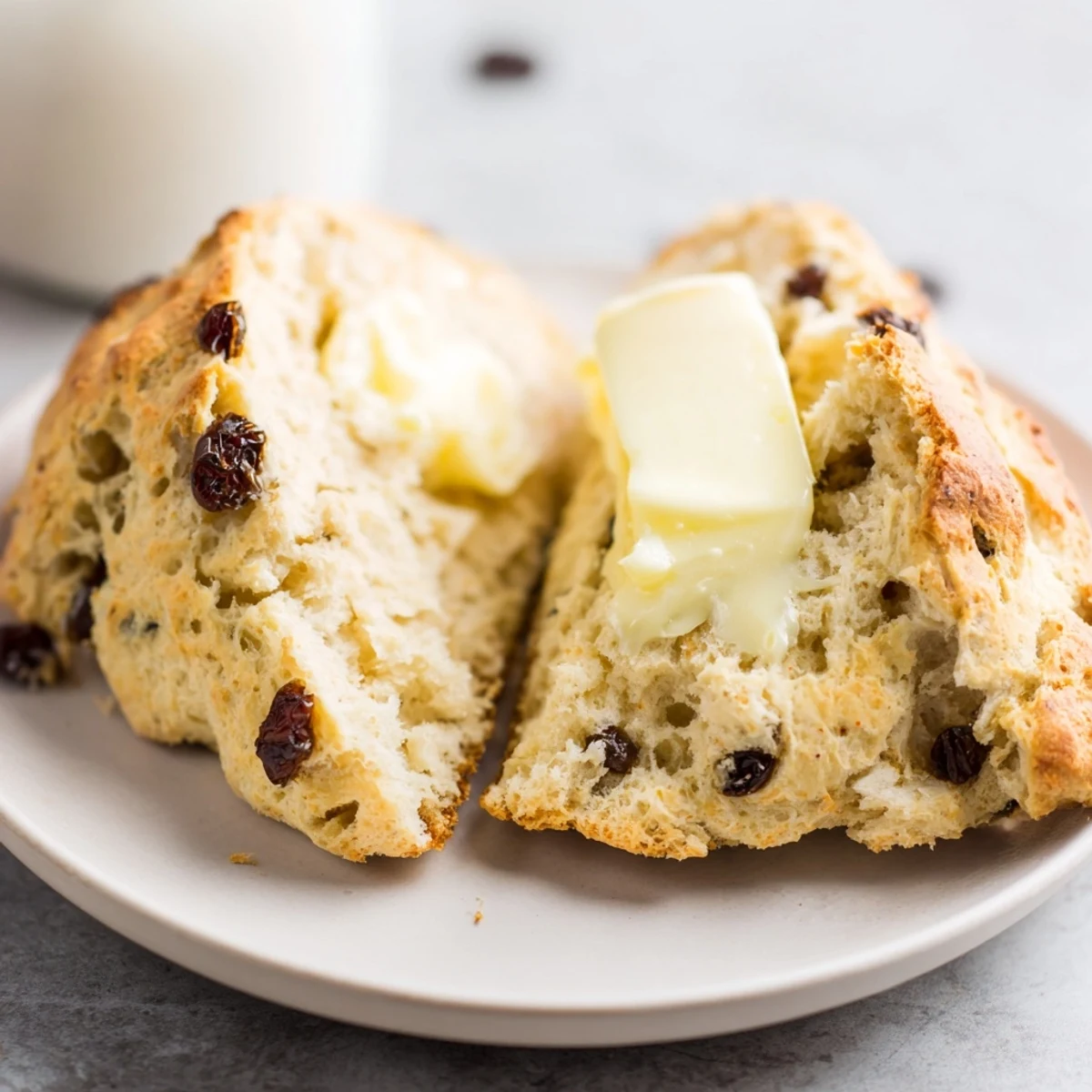 Freshly baked Irish Soda Bread Scones with Butter served warm on a white plate, a pat of butter melting on top.  