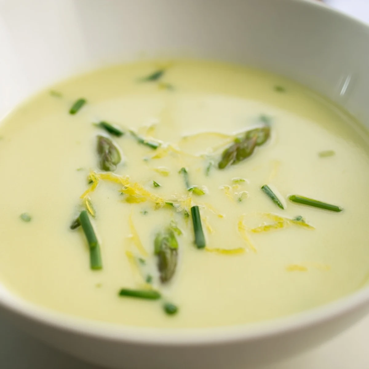 Velvety Creamy Asparagus Soup with Lemon beside crusty bread for dipping on a rustic table