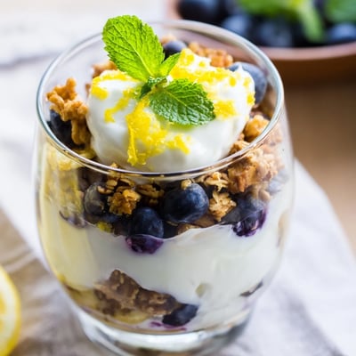 Lemon Blueberry Yogurt Parfait with Granola served in jars topped with extra lemon zest.