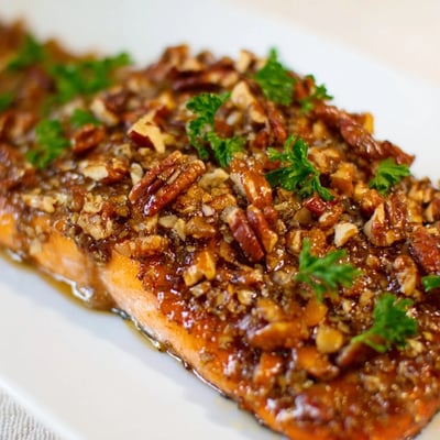 Saftiger Lachs im Ofen mit süßer Ahornsirup-Glasur und knusprigen Pekannüssen serviert.