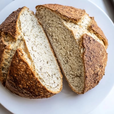 Sliced Irish Soda Bread with Caraway Seeds served beside creamy soup and butter on a wooden table.